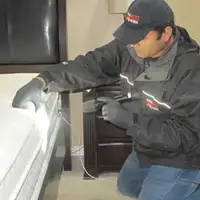 Bed bug inspection technician checking a mattress and bed frame for signs of infestation in Tucson, AZ
