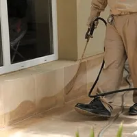 General pest control technician spraying exterior perimeter around a home in Tucson, AZ
