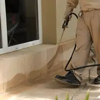 General pest control technician spraying exterior perimeter around a home in Tucson, AZ
