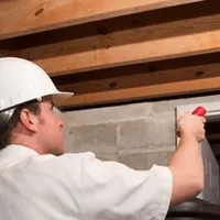 Termite inspection technician checking a basement wall and framing for termite activity in Tucson, AZ