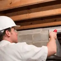 Termite inspection technician checking a basement wall and framing for termite activity in Tucson, AZ