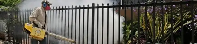 Mosquito control technician fogging a yard perimeter for mosquito reduction in Tucson, AZ
